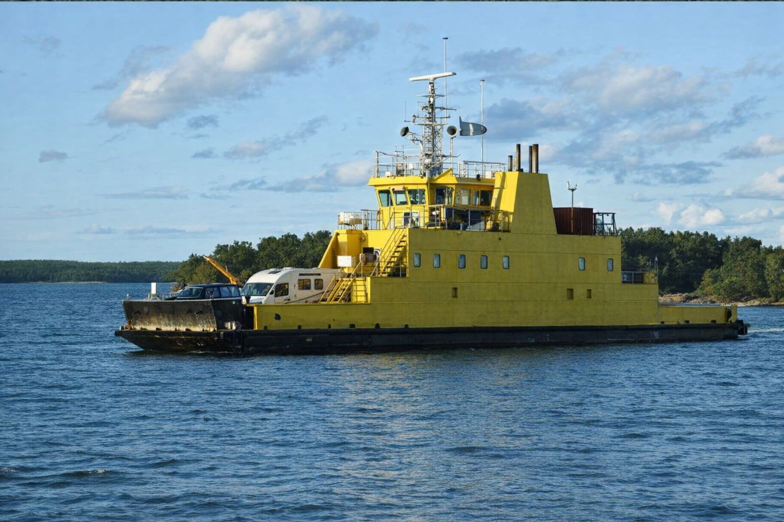 En gul vägfärja transporterar fordon, inklusive en arbetsbil, över vatten.
