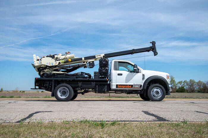 En vit lastbil utrustad med en Geoprobe 3100GT borrvagn på flaket.