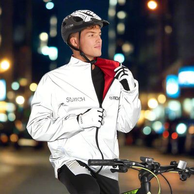 Cyklist i reflekterande jacka med tryck i stadsmiljö på natten.