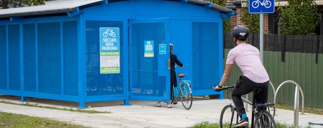 Cyklister vid ett säkert och låst cykelgarage målat i blått.