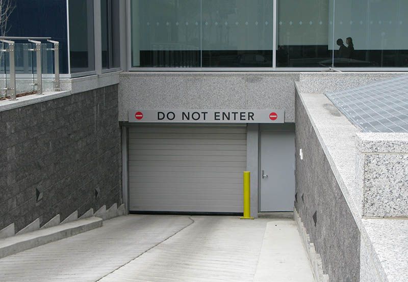 Infart till ett underjordiskt garage med stängd port och skylten DO NOT ENTER.