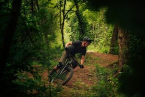 Mountainbikecyklist svänger på en skogsstig bland grönska