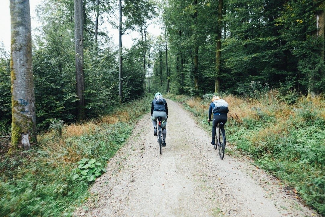 Två cyklister tränar på en grusväg genom skogen